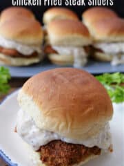 A round white plate with blue trim with a single chicken fried steak slider on it.