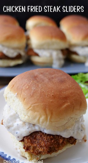 A single chicken fried steak slide on a white plate with blue trim with more sliders in the background.