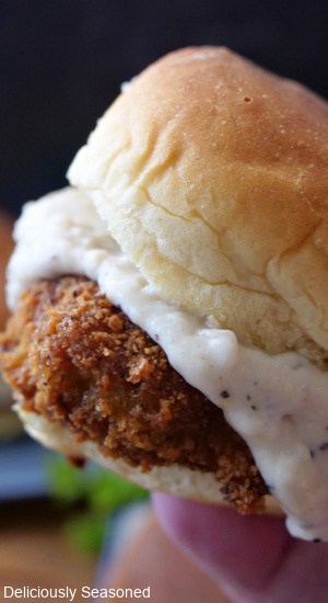 A chicken fried steak slider with the gravy oozing our the sides in between a soft slider bun.