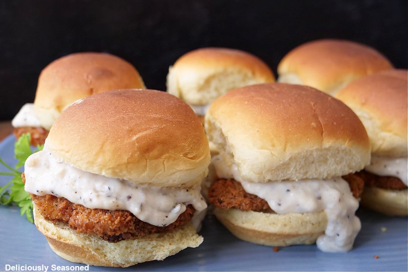 Six sliders on a blue plate showing the crispy fried cube steak, the white gravy, and the soft Hawaiian rolls.