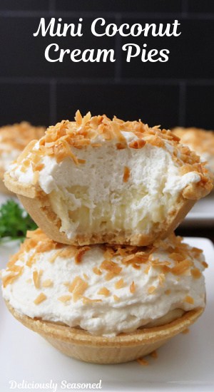 Two mini coconut cream pies with one on top of the other and a bite taken out of the one on top.