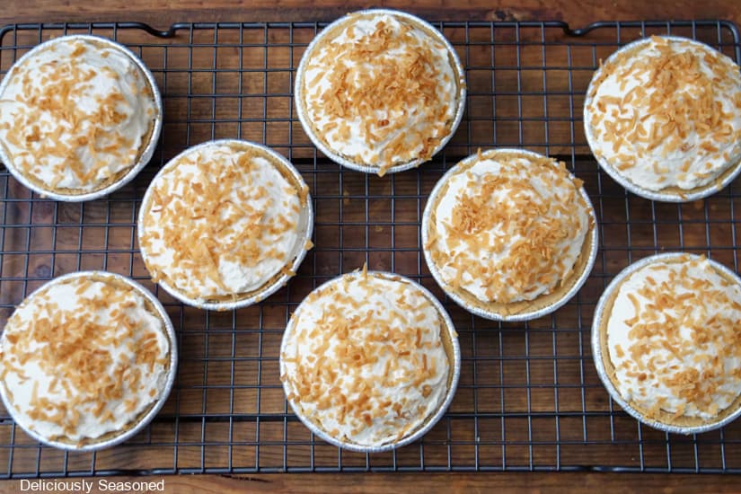 A horizontal photo of 8 mini coconut cream pies on a wire rack.