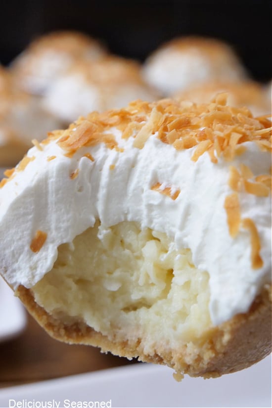 A mini coconut cream pie with a bite taken out of it.
