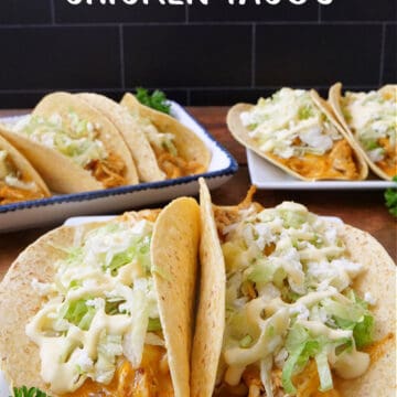 A wood surface with three white plate with baked chicken tacos on them.