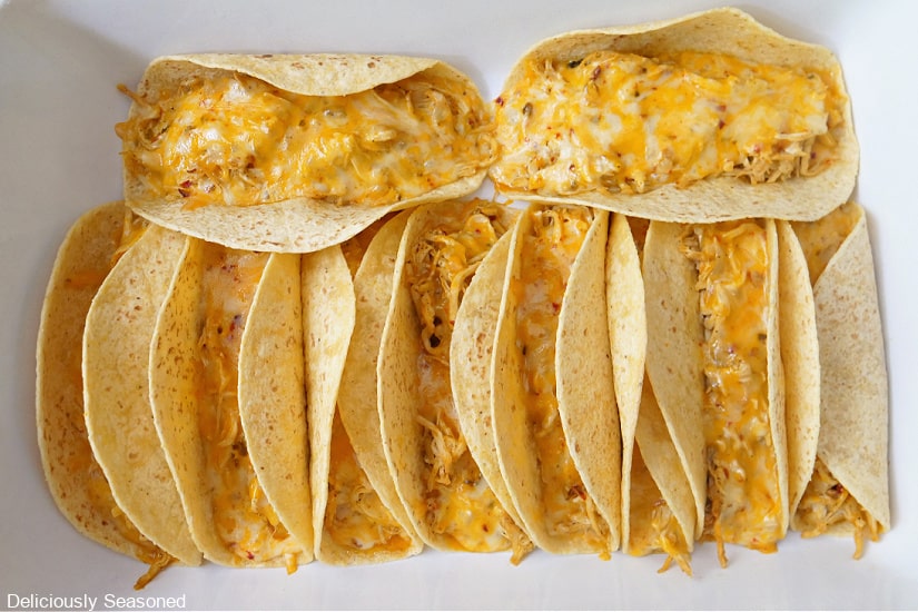 A white baking dish filled with baked chicken tacos after being removed from the oven.