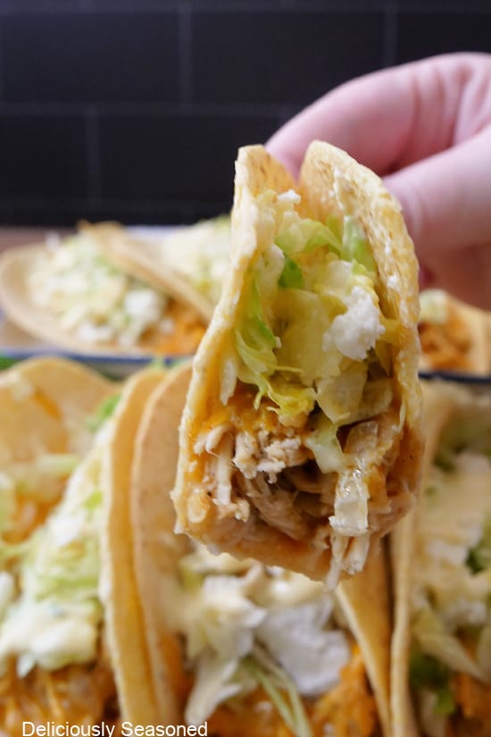 A close up of a chicken taco with a bite taken out of it.