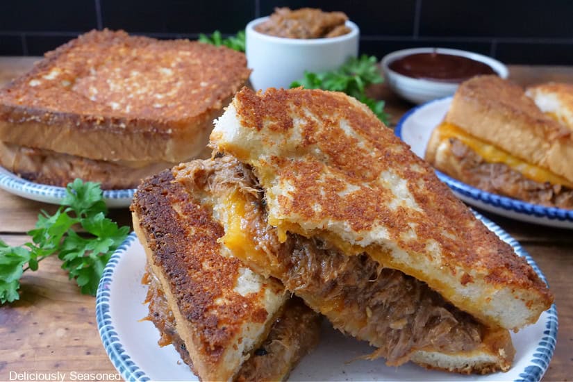 A horizontal photo of three pulled pork grilled cheese sandwiches.
