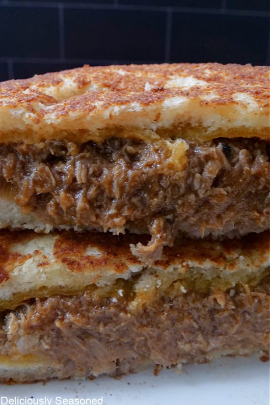 A close up of two pulled pork grilled cheese sandwich halves.