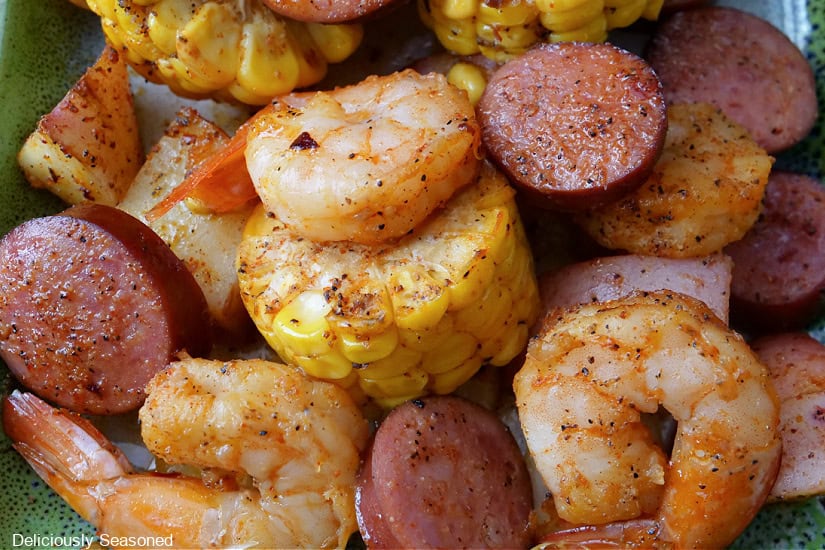 A close up of seasoned shrimp,, sliced sausage, tender potatoes, and corn.