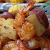 A close up of shrimp, sliced smoked sausage, potatoes, and corn.