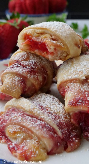 A close up of a few bite-size strawberry pastries with a bite taken out of the one on top.
