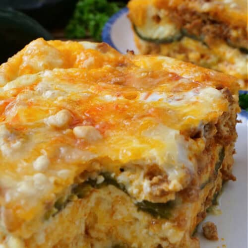 A serving of chile relleno casserole with chorizo on a white plate with a bite taken out.