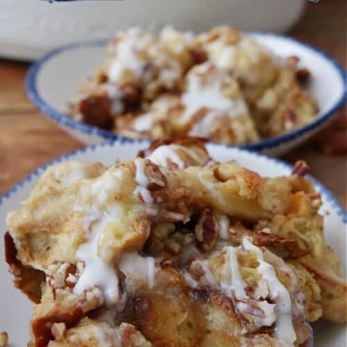 Two white bowls with blue trim filled with southern butter pecan bread pudding.