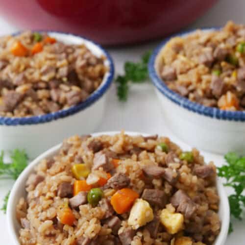 Three white bowls filled with steak fried rice on a table.