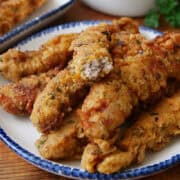 Steak fingers on a white plate with blue trim.