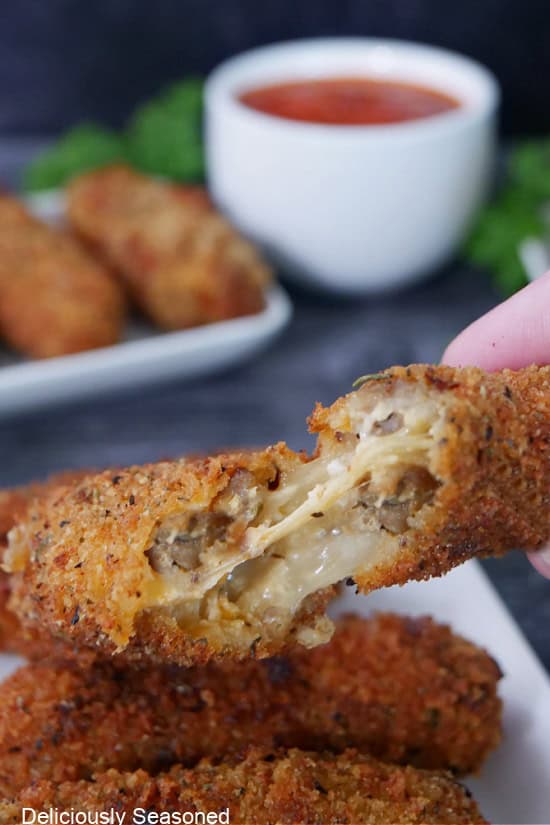 A spicy mozzarella stick being pulled apart to show the cheese insides.