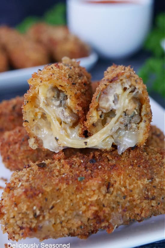 A cheesy Italian sausage mozzarella stick cut in half showing all the melty cheese on the inside.