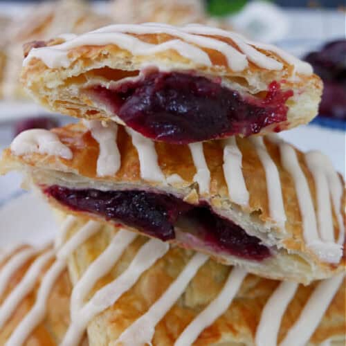 Four pieces of cherry toaster strudel stacked on top of one another with a bite out of the one on top.