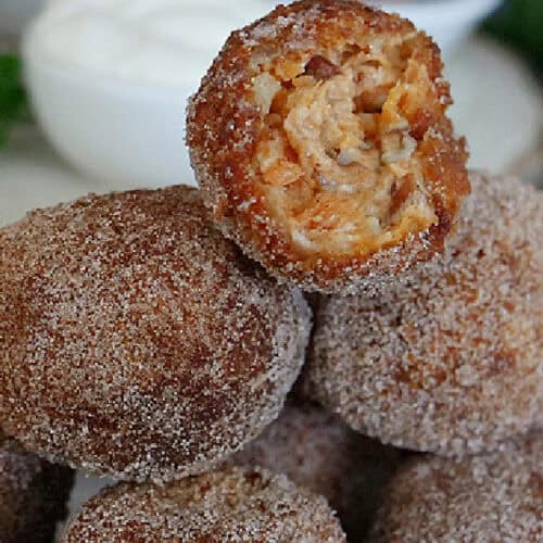 Deep fried sweet potato bites stacked on each other with a bite taken out of the one on top.
