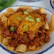 A white bowl with blue trim filled with a serving of chili cheese Fritos.