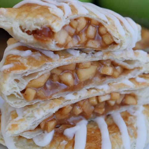 A white plate with a few apple filled toaster strudels stacked on top of each other.