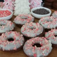 A wood surface with iced chocolate donuts on it.