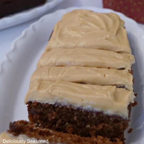 A sliced frosted gingerbread loaf on a white plate.