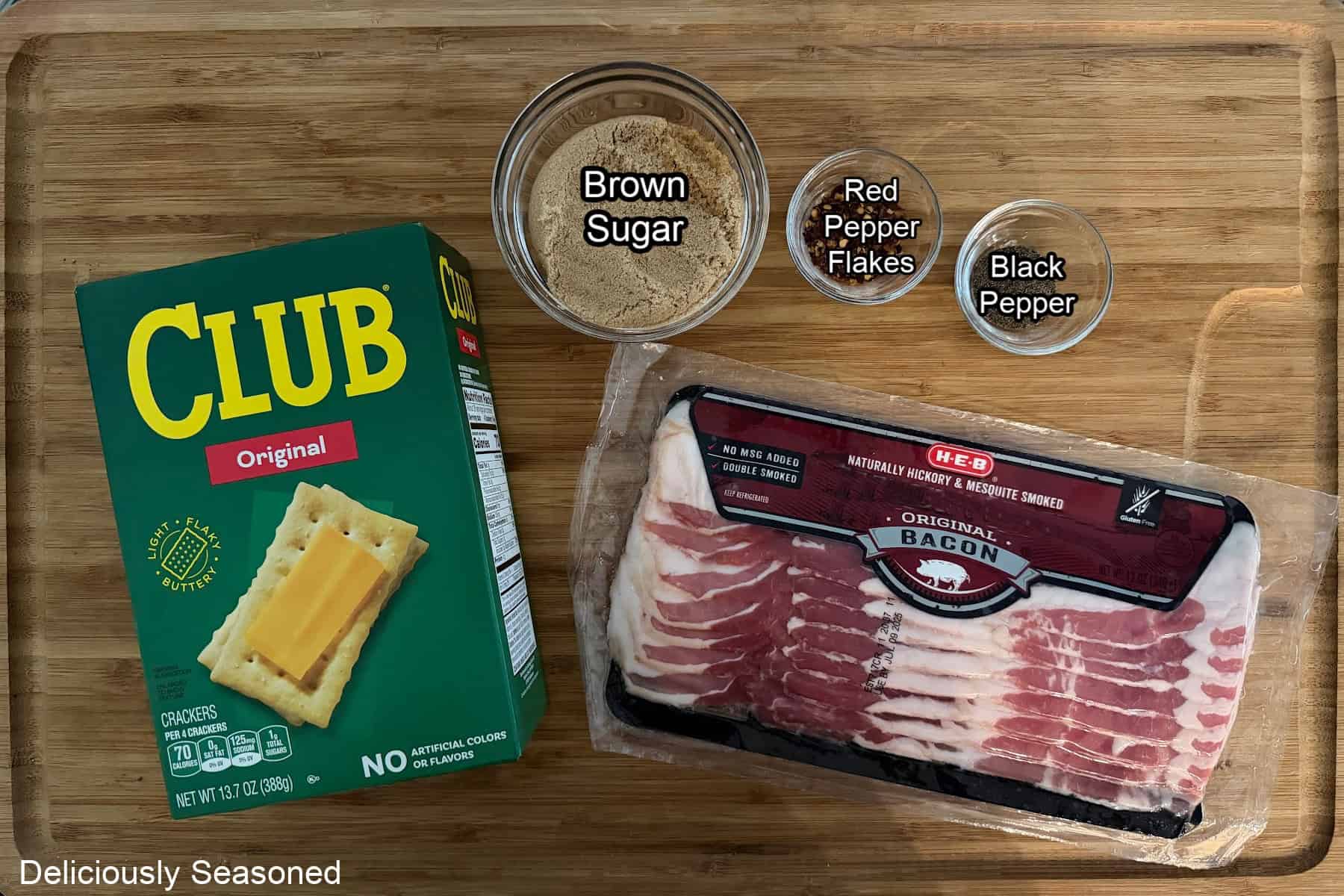 A wood surface with the 5-ingredients needed to make candied bacon crackers.