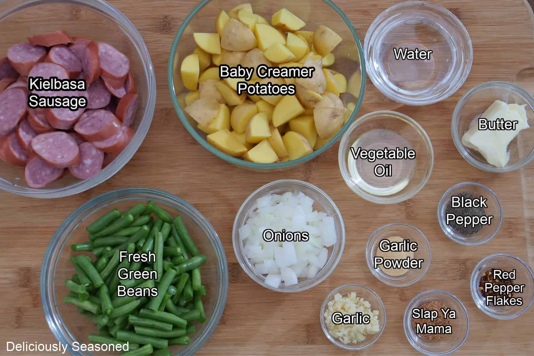 A wood surface with all the ingredients on it to make sausage green beans and potatoes.
