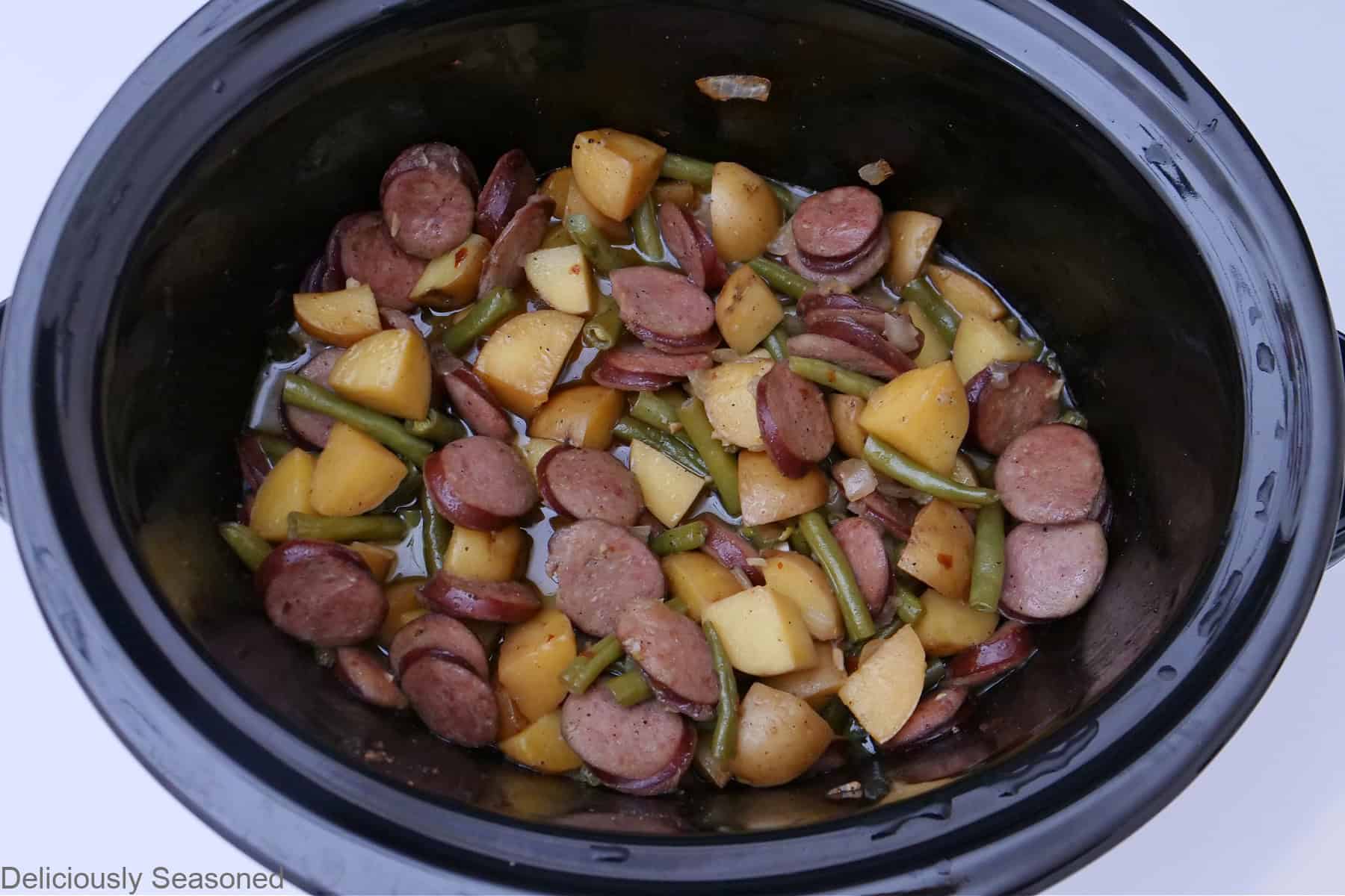 An overhead look into the crock pot of sausage, green beans, and potatoes.