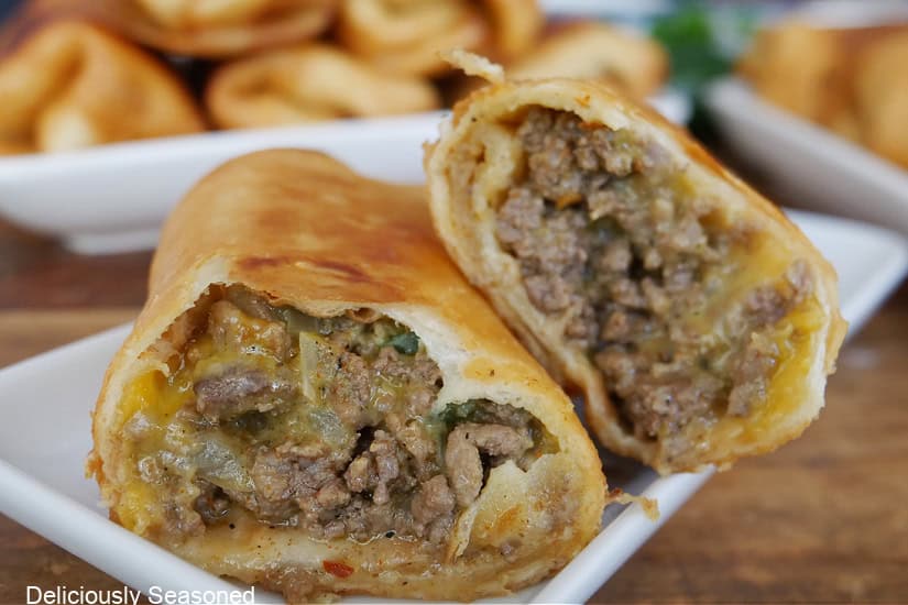A white square plate with a fried beef burrito cut in half and placed on the plate.