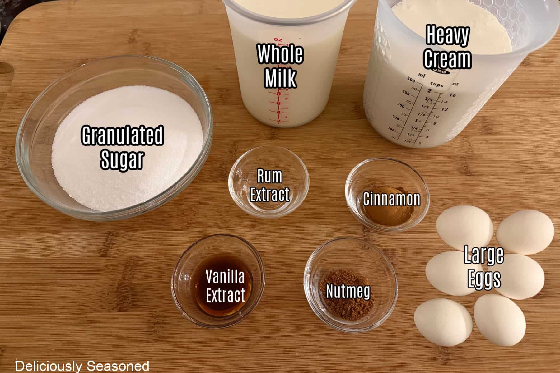 A wood surface with all the ingredients to make homemade eggnog on it.