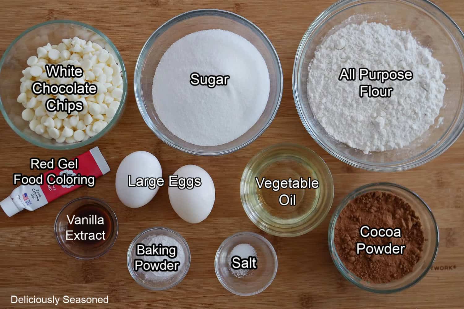 A wood surface with all the ingredients needed to make red velvet cookies.