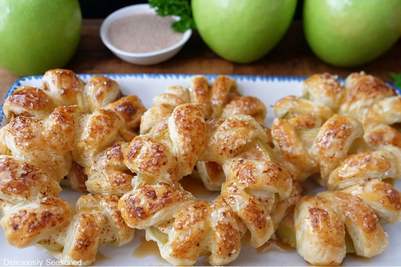 A white oblong plate with six apple pastry rings on it