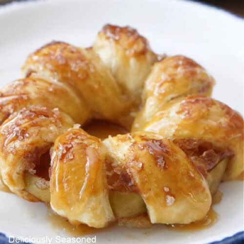 A white plate with blue trim with one apple pastry ring on it.