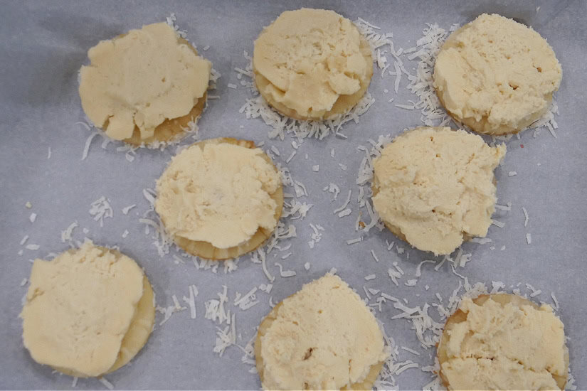 A parchment lined baking sheet with pineapple upside down cookies on it that are about to go in the oven.