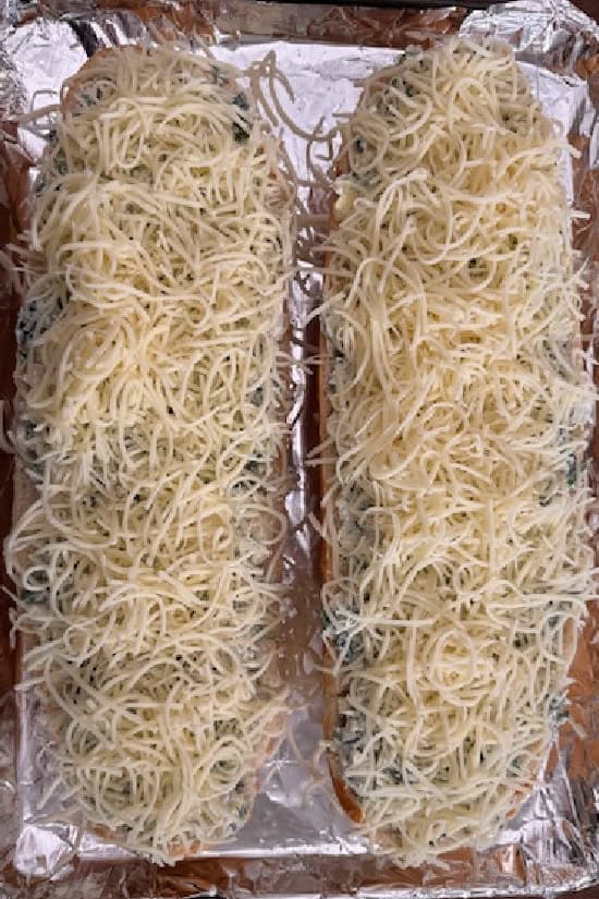 A foil lined baking sheet with mozzarella cheese spread over the top.