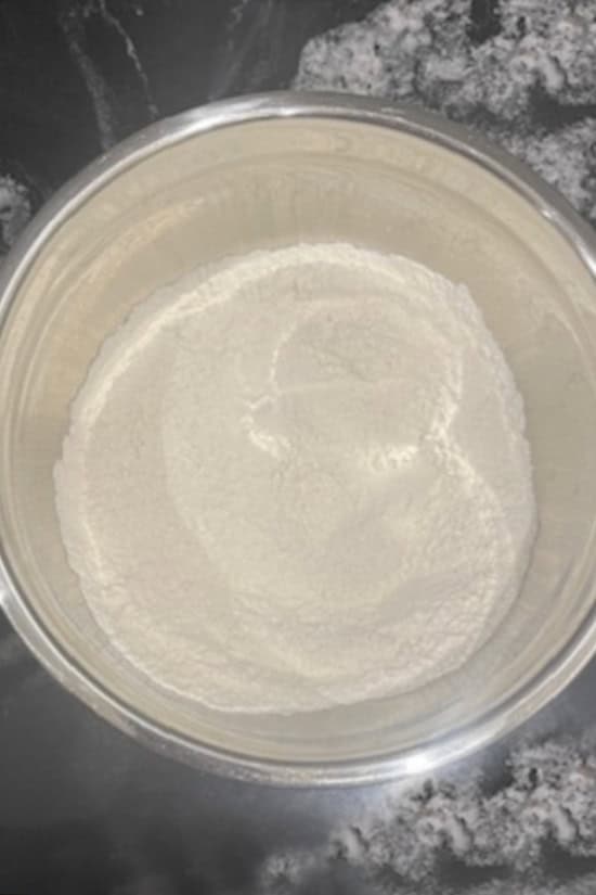 A silver mixing bowl with dry cookie ingredients in it.