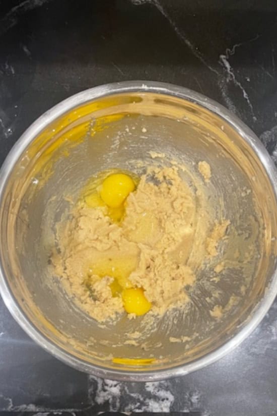A silver bowl with the wet cookie ingredients in it.
