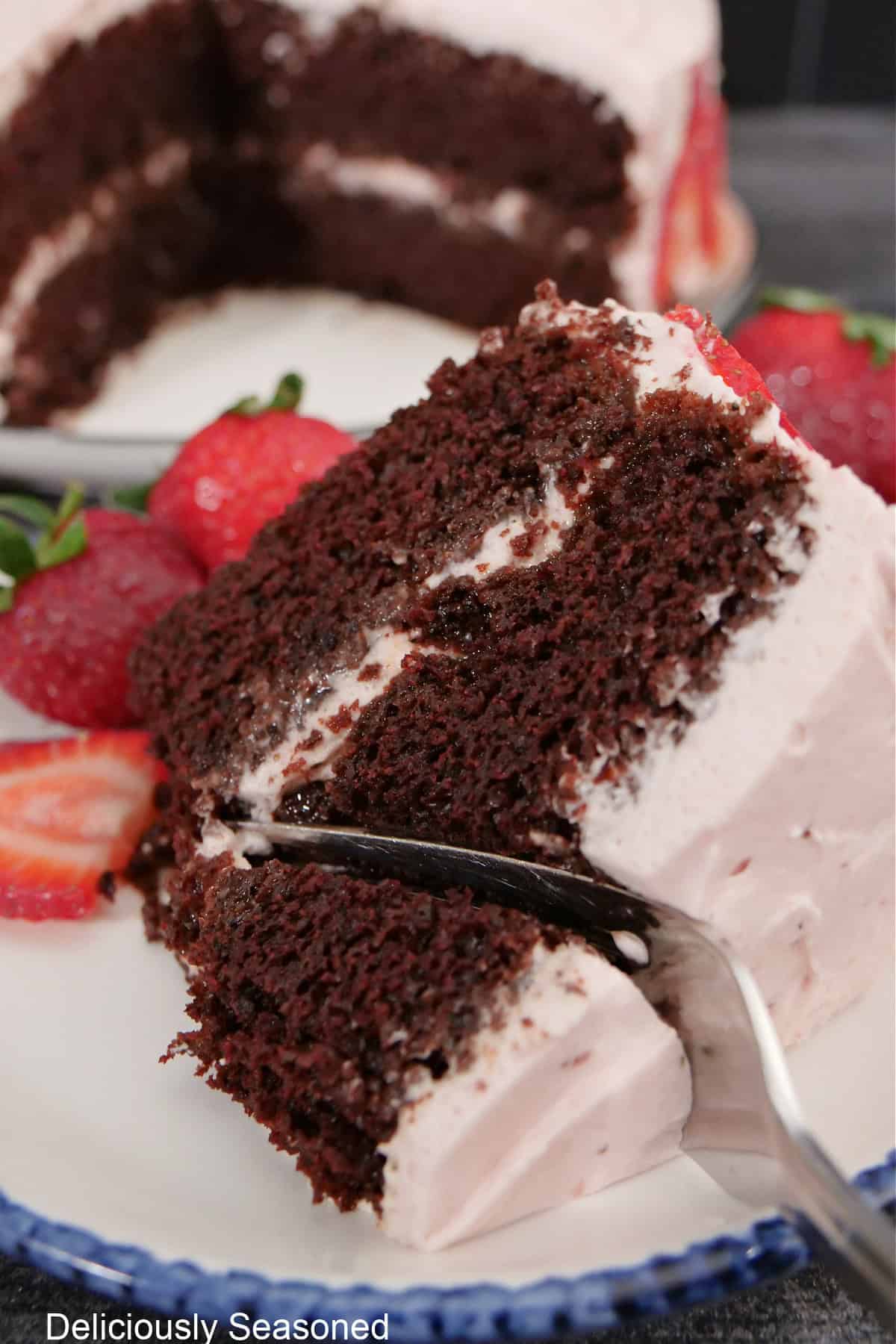 A slice of chocolate cake with a fork pressed down getting a bite on it.