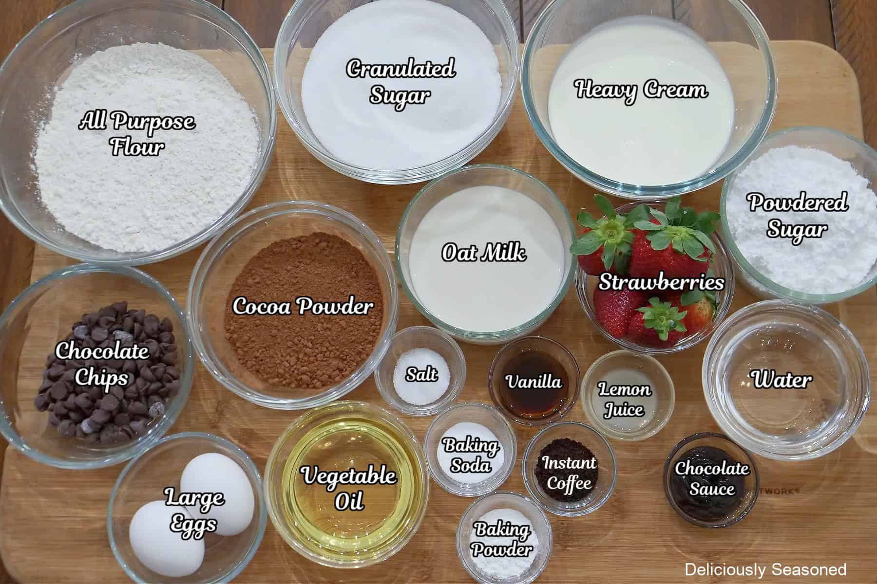 A wood surface with all the ingredients placed on it needed to make strawberry chocolate cake.