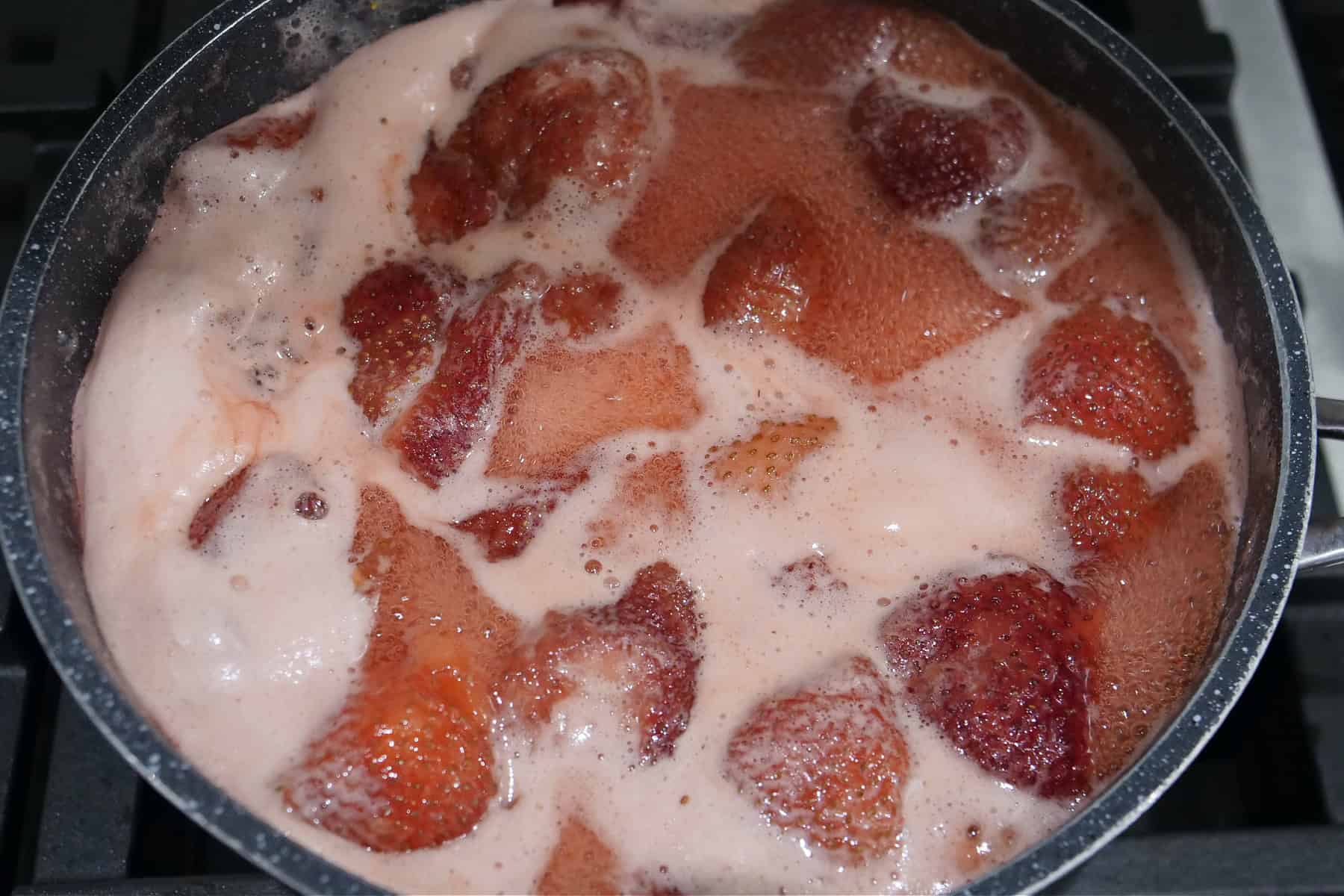 A saucepan with fresh strawberries boiling in it.