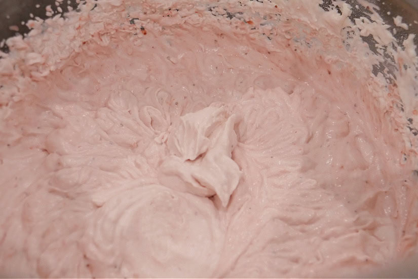 A bowl filled with whipped strawberry frosting.