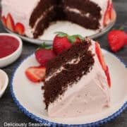 A slice of a layered chocolate cake with a whipped strawberry frosting.