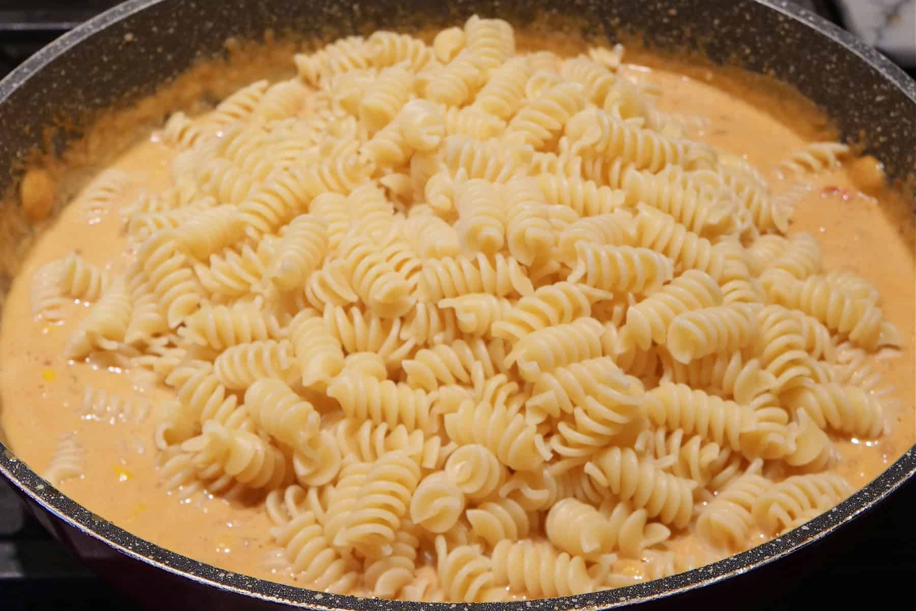 A skillet with pasta and creamy sauce in it.