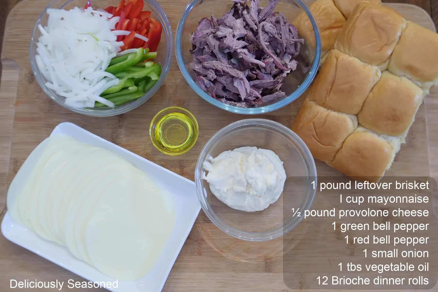 A wood surface with the ingredients to make leftover brisket philly sliders on it with the amount of each ingredient typed out.