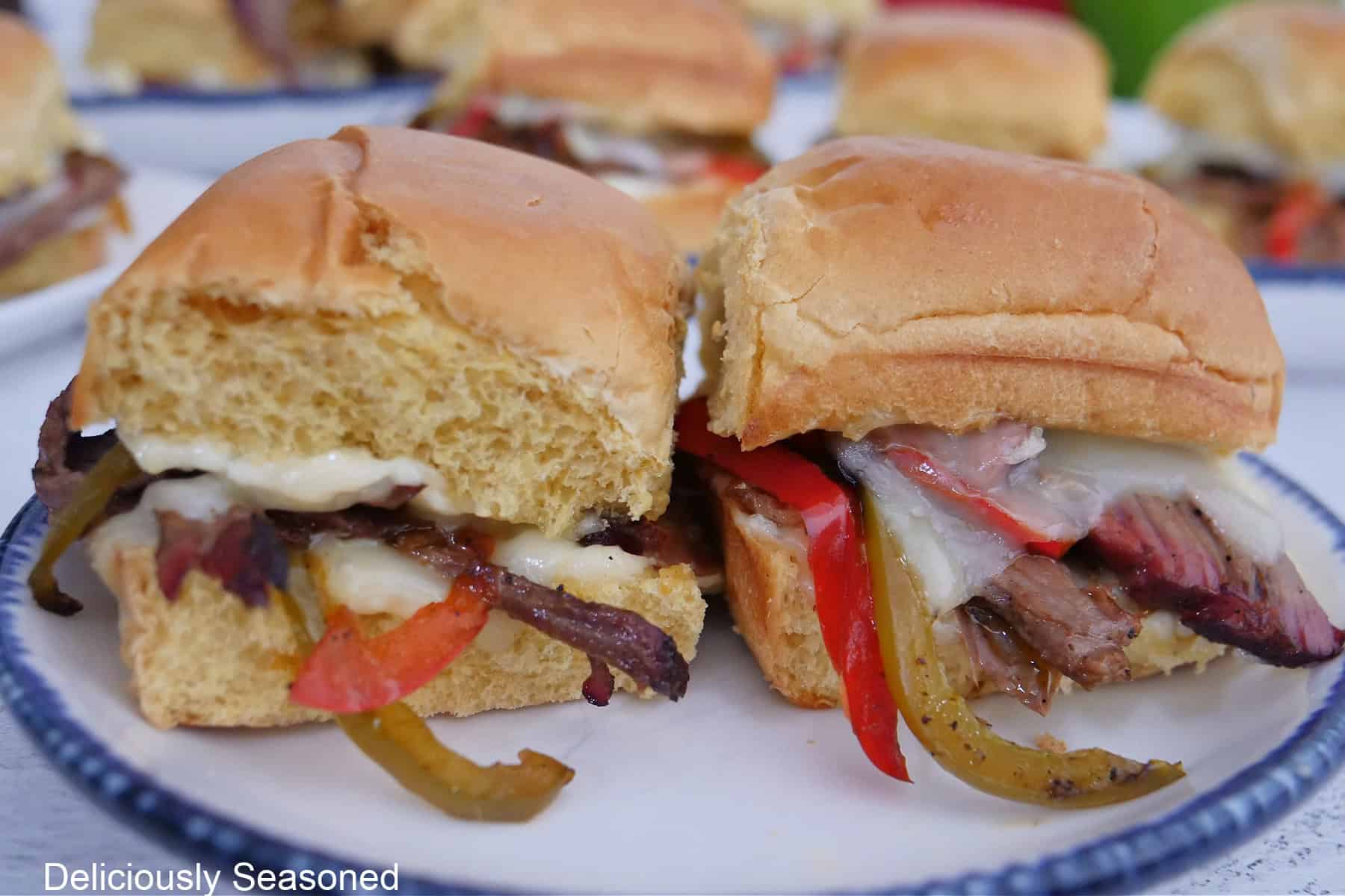 A round white plate with blue trim with two brisket sliders on it.