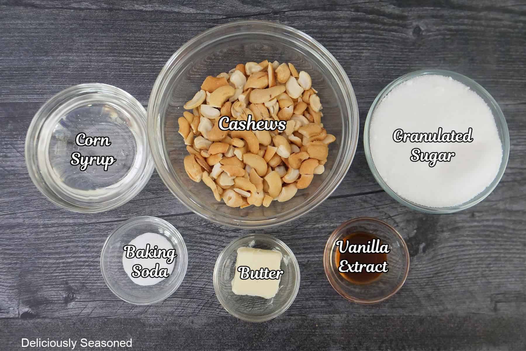A grey surface with 6 glass bowls on it filled with the ingredients to make cashew brittle.
