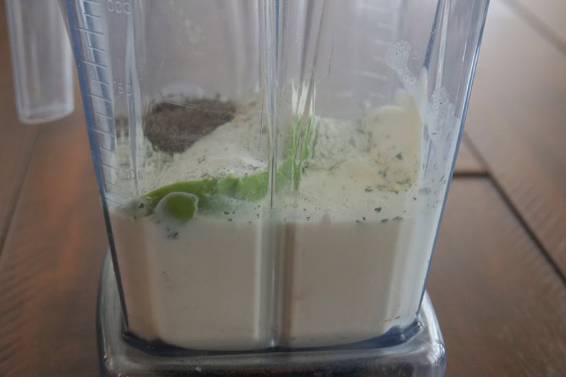 A vitamix with avocado ranch dressing ingredients in it before being blended.