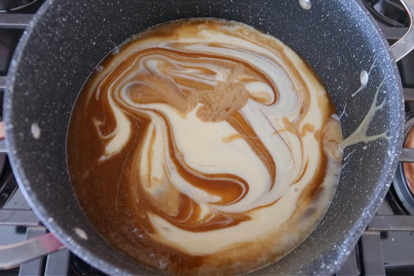 A pan with melted brown sugar and butter with corn syrup and condensed milk added.